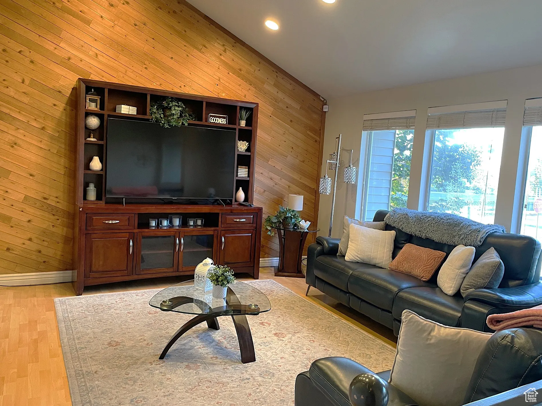 Living room featuring wood walls, light wood-style flooring, and recessed lighting