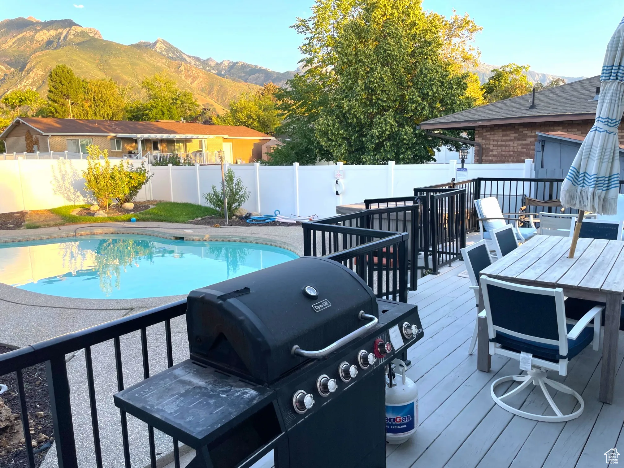View of pool with area for grilling, a deck with mountain view, a fenced backyard, and outdoor dining space