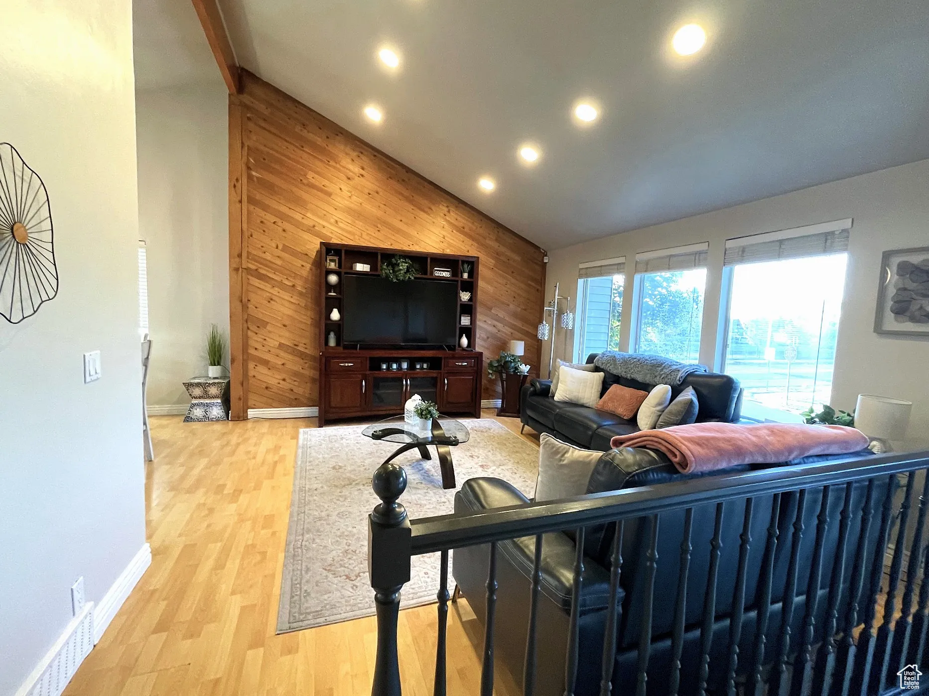 Living area featuring wooden walls, light wood-style flooring, high vaulted ceiling, and recessed lighting