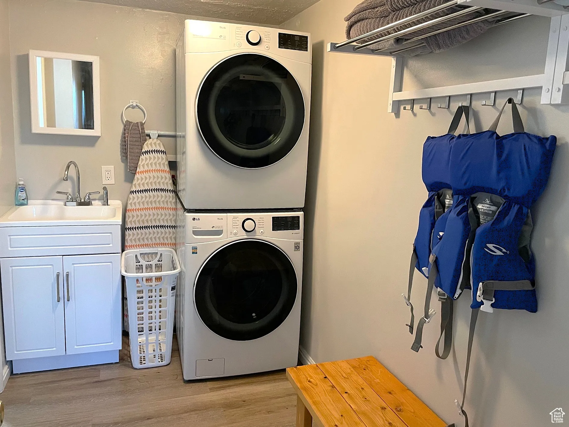 Laundry area with light wood-style flooring and stacked washer / dryer