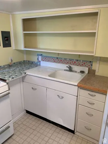 Kitchen featuring white cabinetry, white range oven, open shelves, electric panel, and tasteful backsplash