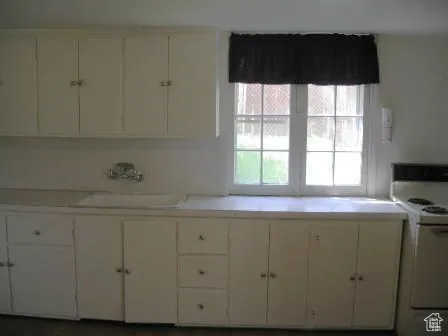 Kitchen with white range with electric cooktop, light countertops, and white cabinetry