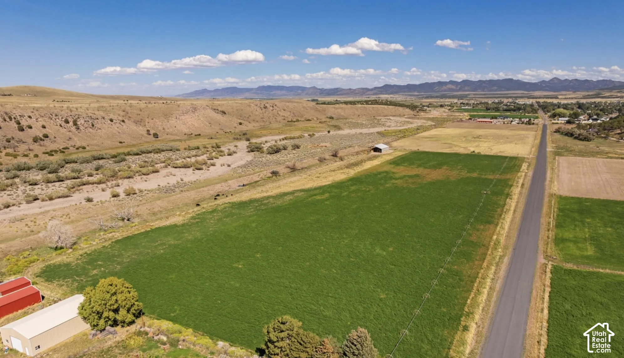 Expansive agricultural fields with distant mountains, a paved road, and a distant riverbed
