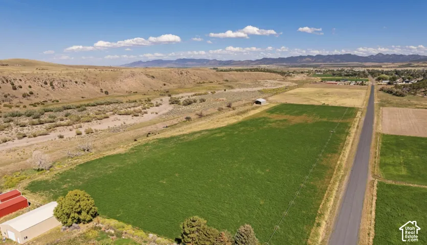 Expansive agricultural fields with distant mountains, a paved road, and a distant riverbed