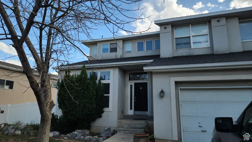 View of front of home with roof with shingles, a garage, and stucco siding
