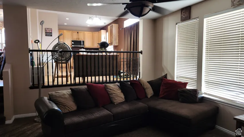 Living area featuring ceiling fan, dark colored carpet, and recessed lighting