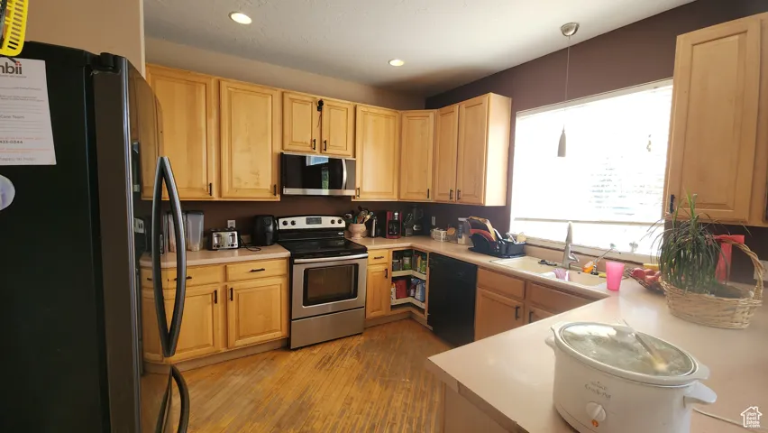 Kitchen with black appliances, light brown cabinets, light countertops, recessed lighting, and light wood-style flooring