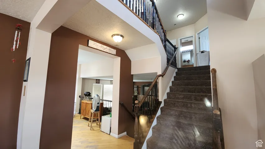 Stairway with a textured ceiling and wood finished floors