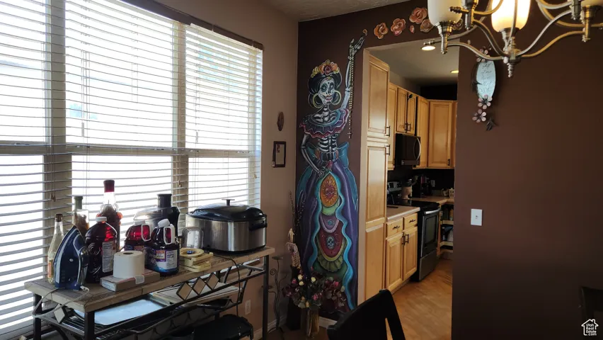 Kitchen with stainless steel electric range oven, a chandelier, light countertops, black microwave, and light wood finished floors