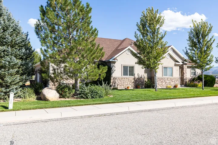 View of front of home featuring stone siding, a front yard, stucco siding, and roof with shingles