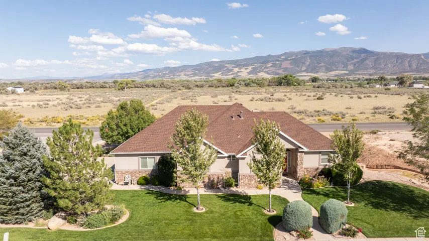 View of front of home featuring stone siding, a mountain view, stucco siding, and a front yard