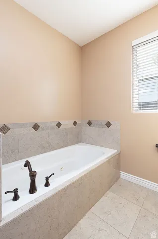 Full bath with a garden tub and light tile patterned flooring