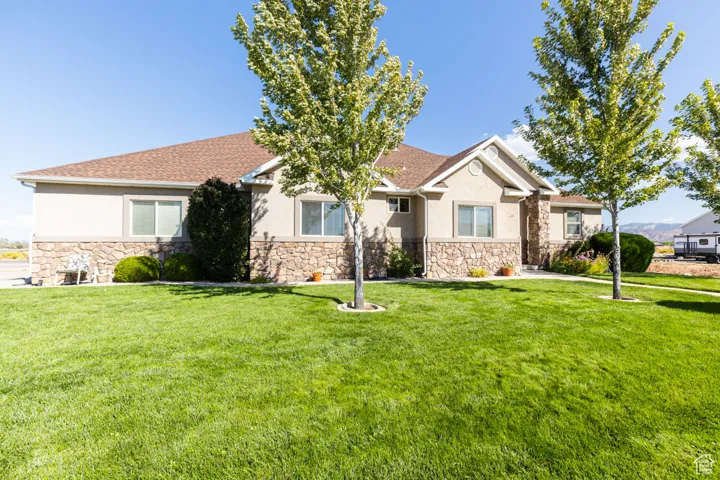 View of front of home featuring stone siding, stucco siding, and a front lawn