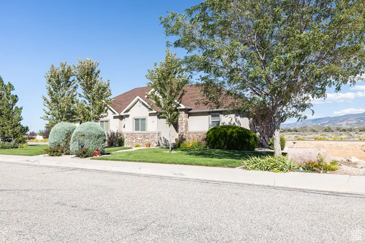 View of front of home featuring stucco siding, a front lawn, and stone siding