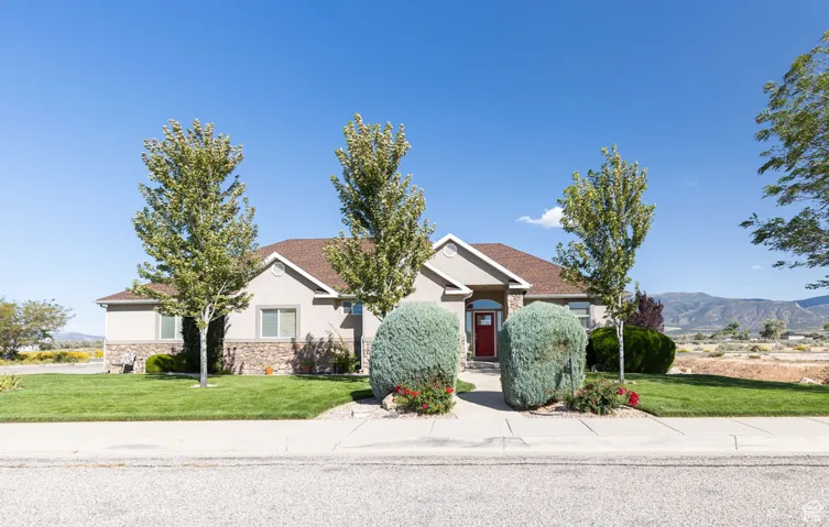 View of front of property featuring a front yard, stone siding, stucco siding, and a mountain view