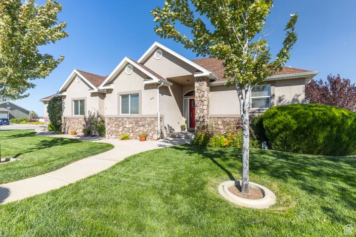 View of front of home with stone siding, stucco siding, and a front lawn