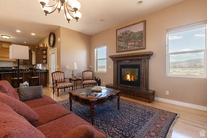 Living room with light wood finished floors, a chandelier, a premium fireplace, and recessed lighting