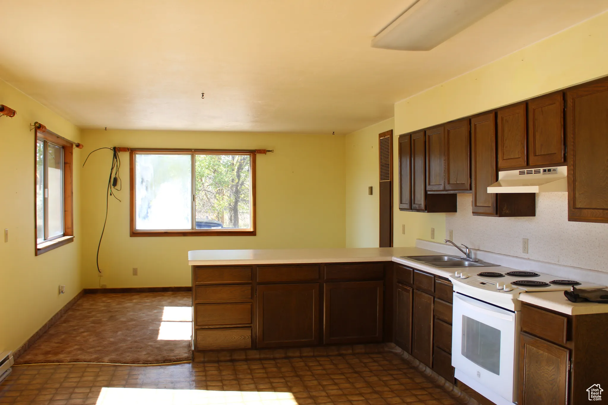 Kitchen with a peninsula, electric range, plenty of natural light, and light countertops