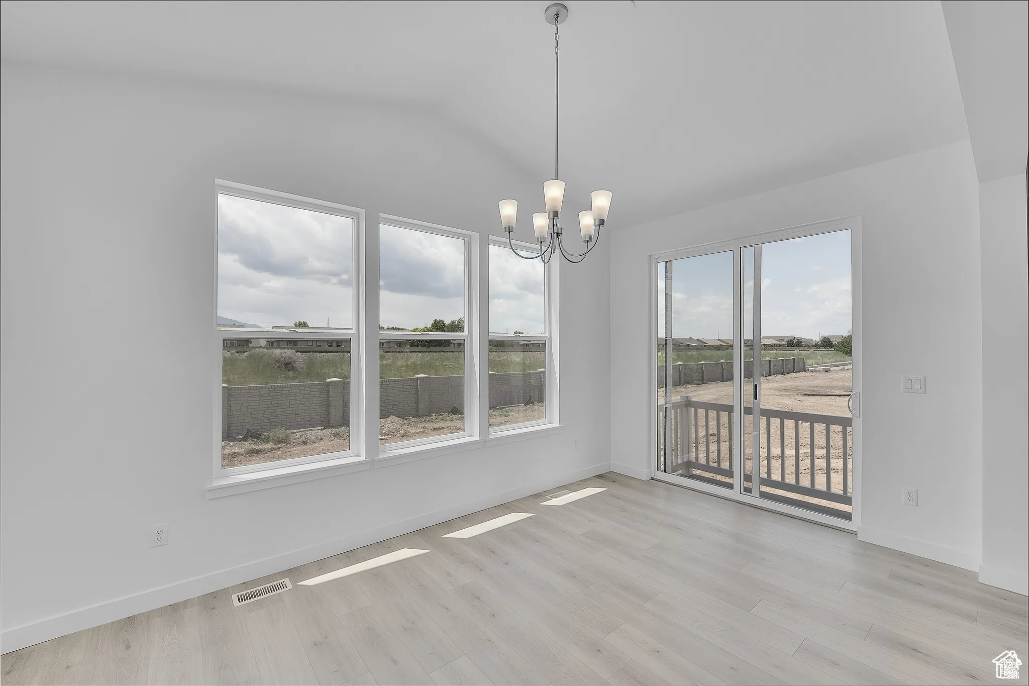 Unfurnished dining area featuring a chandelier and light wood-style floors