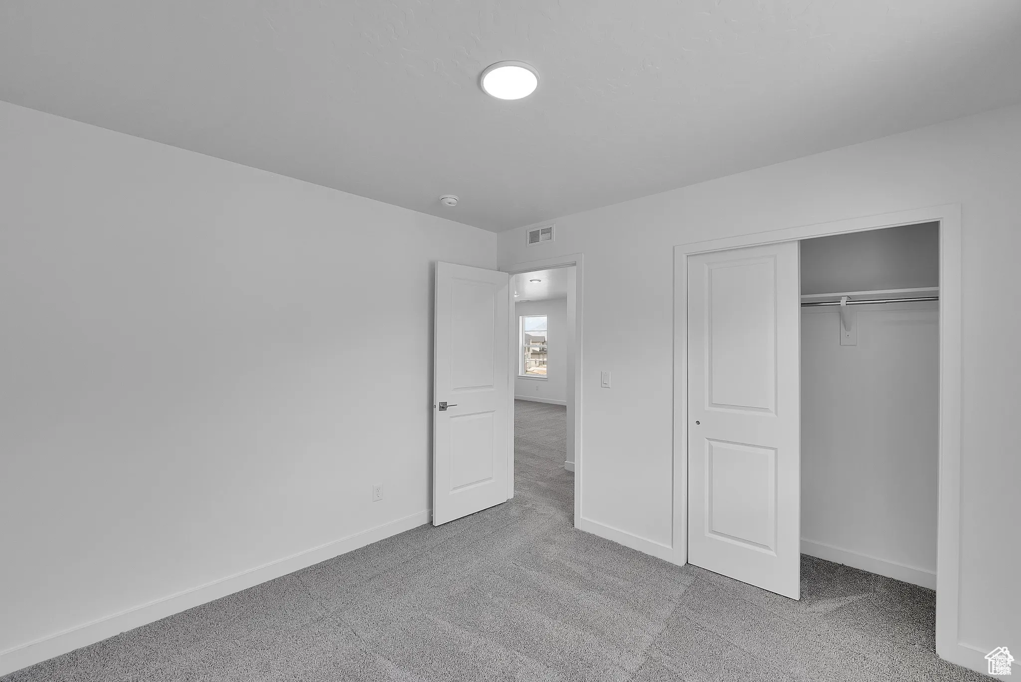 Unfurnished bedroom with light colored carpet and a closet