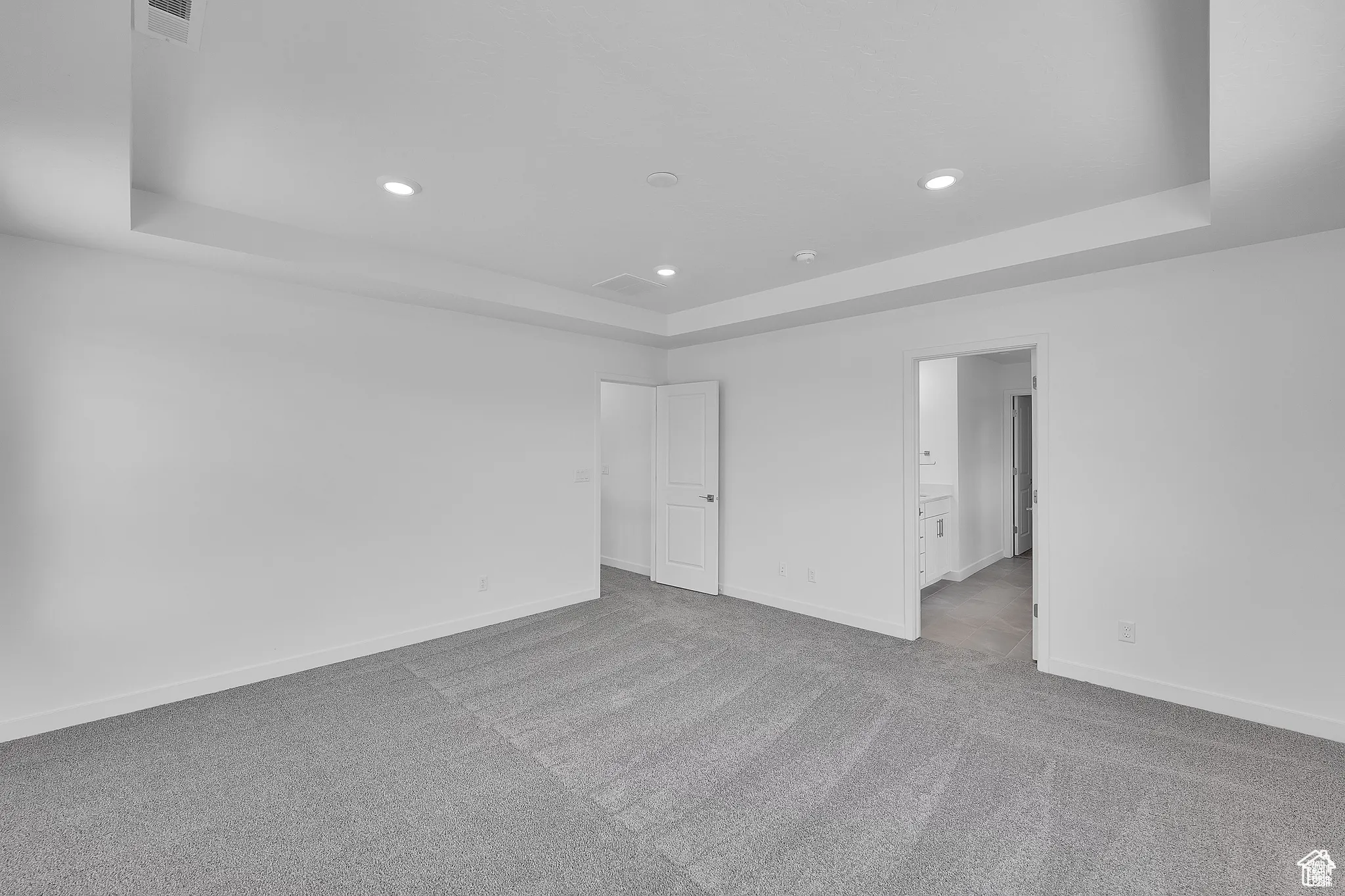 Spare room featuring a tray ceiling, light colored carpet, and recessed lighting