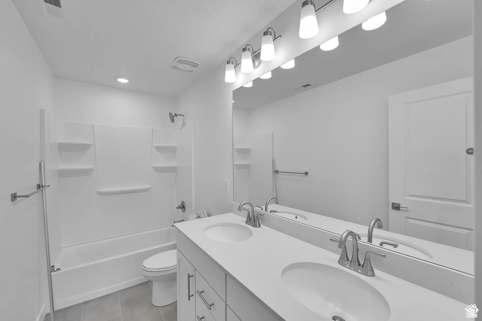 Full bath with shower / washtub combination, double vanity, and light tile patterned floors