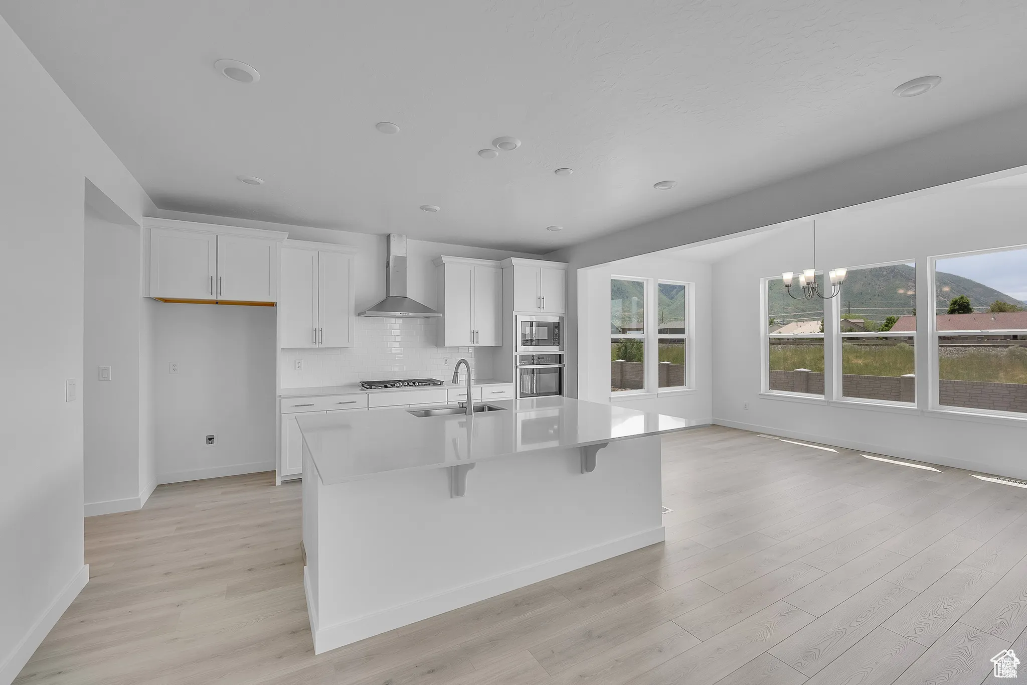 Kitchen with white cabinets, light wood finished floors, a kitchen breakfast bar, a chandelier, and recessed lighting