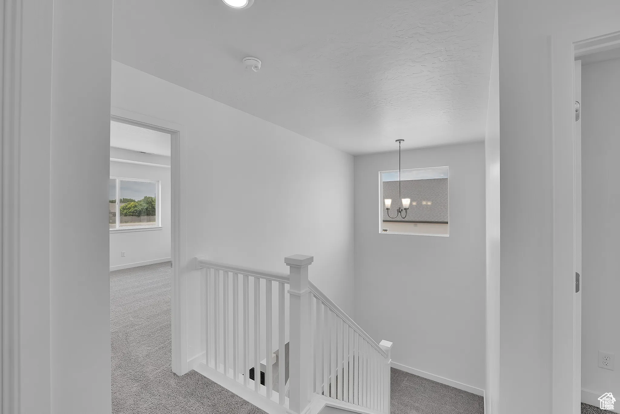 Hallway featuring an upstairs landing, carpet, and a chandelier