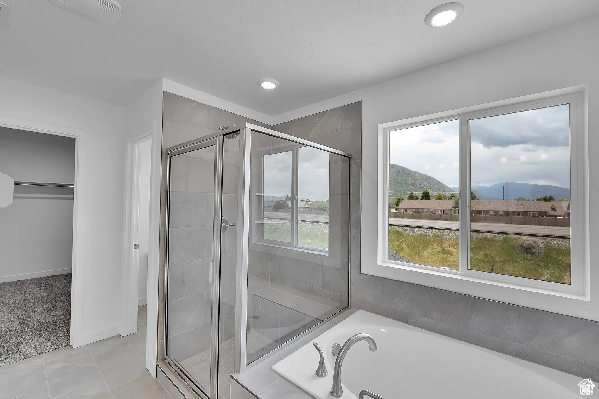 Full bath featuring a mountain view, a shower stall, a garden tub, light tile patterned flooring, and recessed lighting