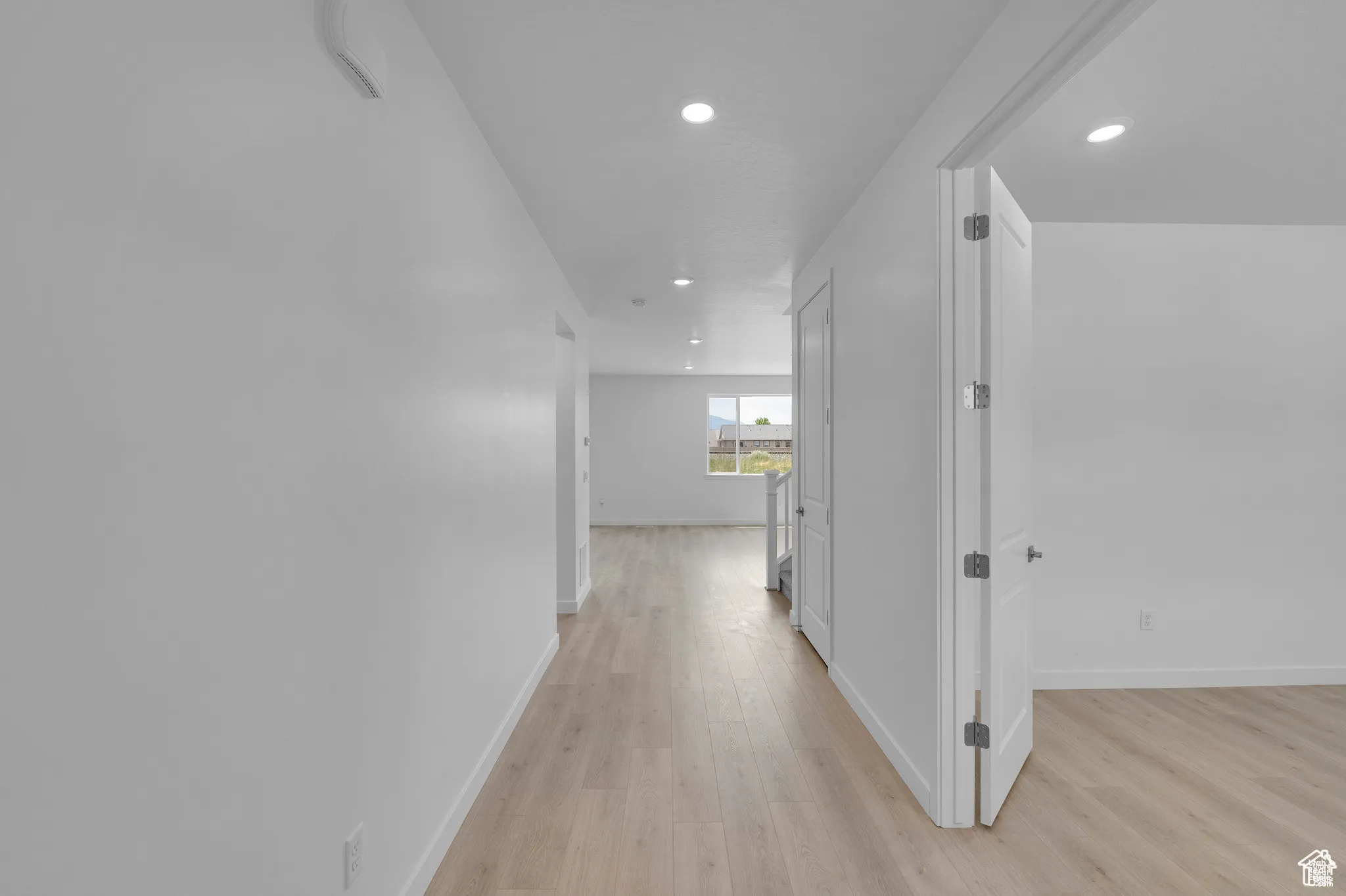 Corridor with light wood-style flooring and recessed lighting