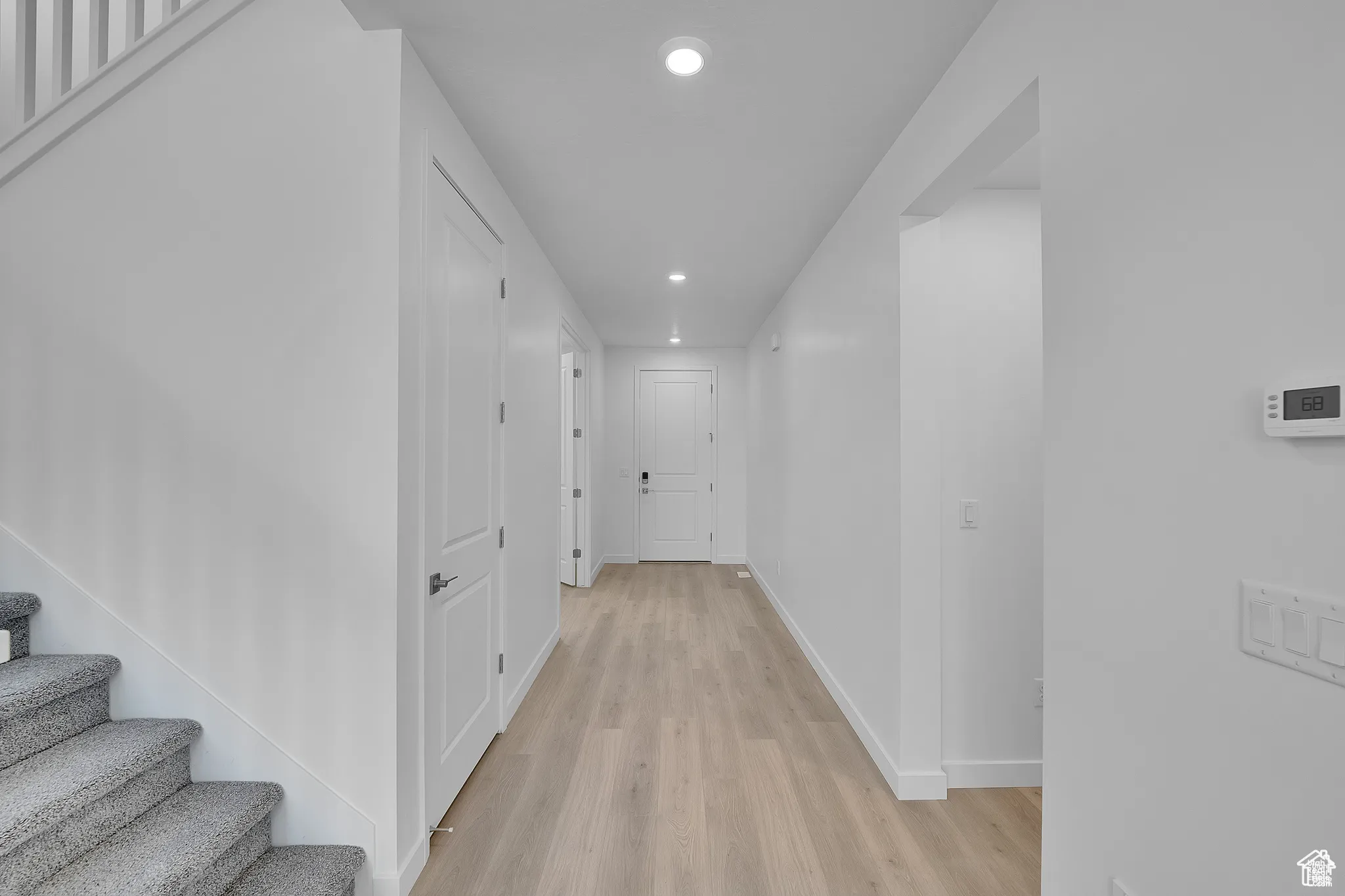 Hall with recessed lighting, light wood finished floors, and stairs