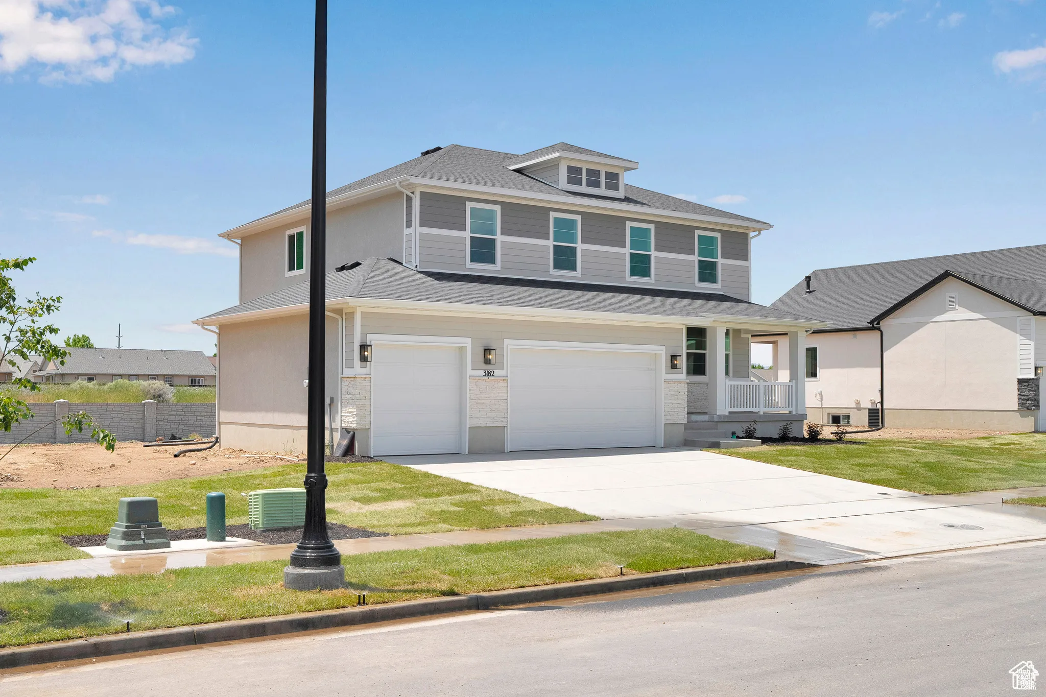 View of front facade with an attached garage, driveway, a front lawn, roof with shingles, and covered porch