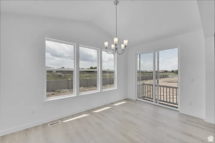 Unfurnished dining area featuring a chandelier and light wood-style floors