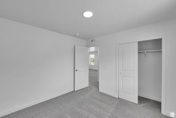 Unfurnished bedroom with light colored carpet and a closet