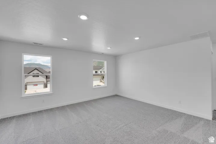 Spare room featuring light colored carpet, recessed lighting, and a textured ceiling