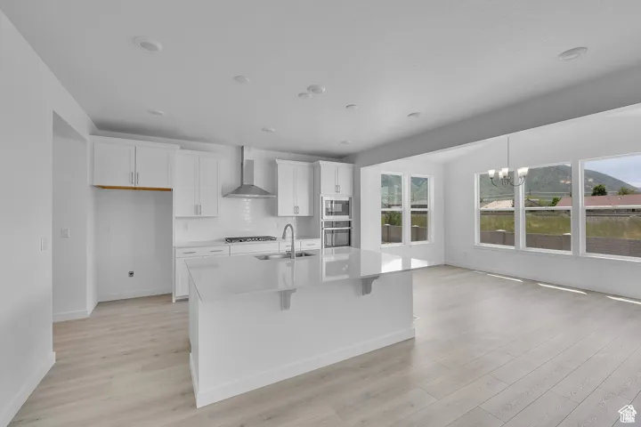 Kitchen with white cabinets, light wood finished floors, a kitchen breakfast bar, a chandelier, and recessed lighting