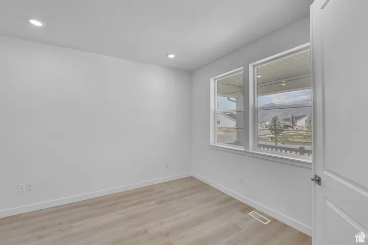 Empty room with light wood-style floors and recessed lighting
