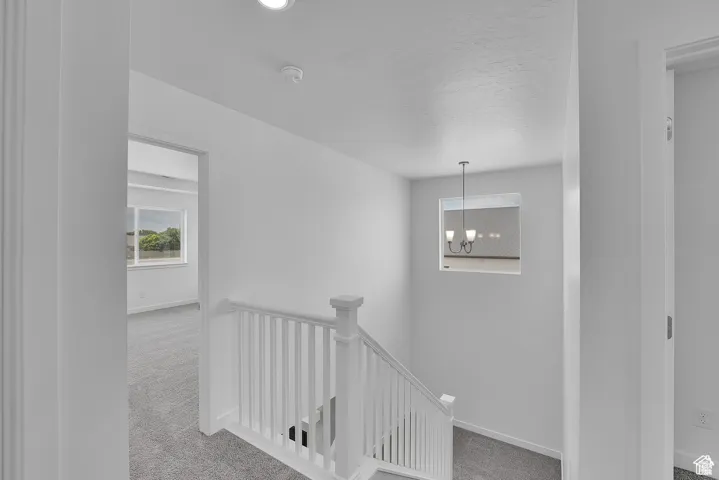 Hallway featuring an upstairs landing, carpet, and a chandelier
