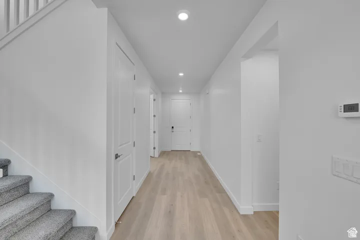 Hall with recessed lighting, light wood finished floors, and stairs