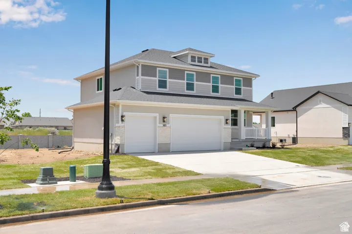 View of front facade with an attached garage, driveway, a front lawn, roof with shingles, and covered porch