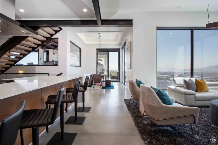 Living room featuring stairs, concrete flooring, a raised ceiling, and recessed lighting