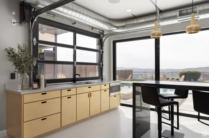 Interior space with light brown cabinets, light countertops, concrete flooring, and stainless steel microwave