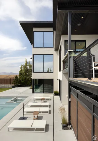 Back of house featuring stucco siding, a pool with connected hot tub, a mountain view, and a patio