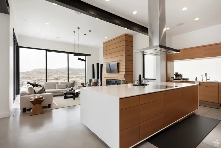 Kitchen with beam ceiling, modern cabinets, island range hood, a large island, and light stone counters