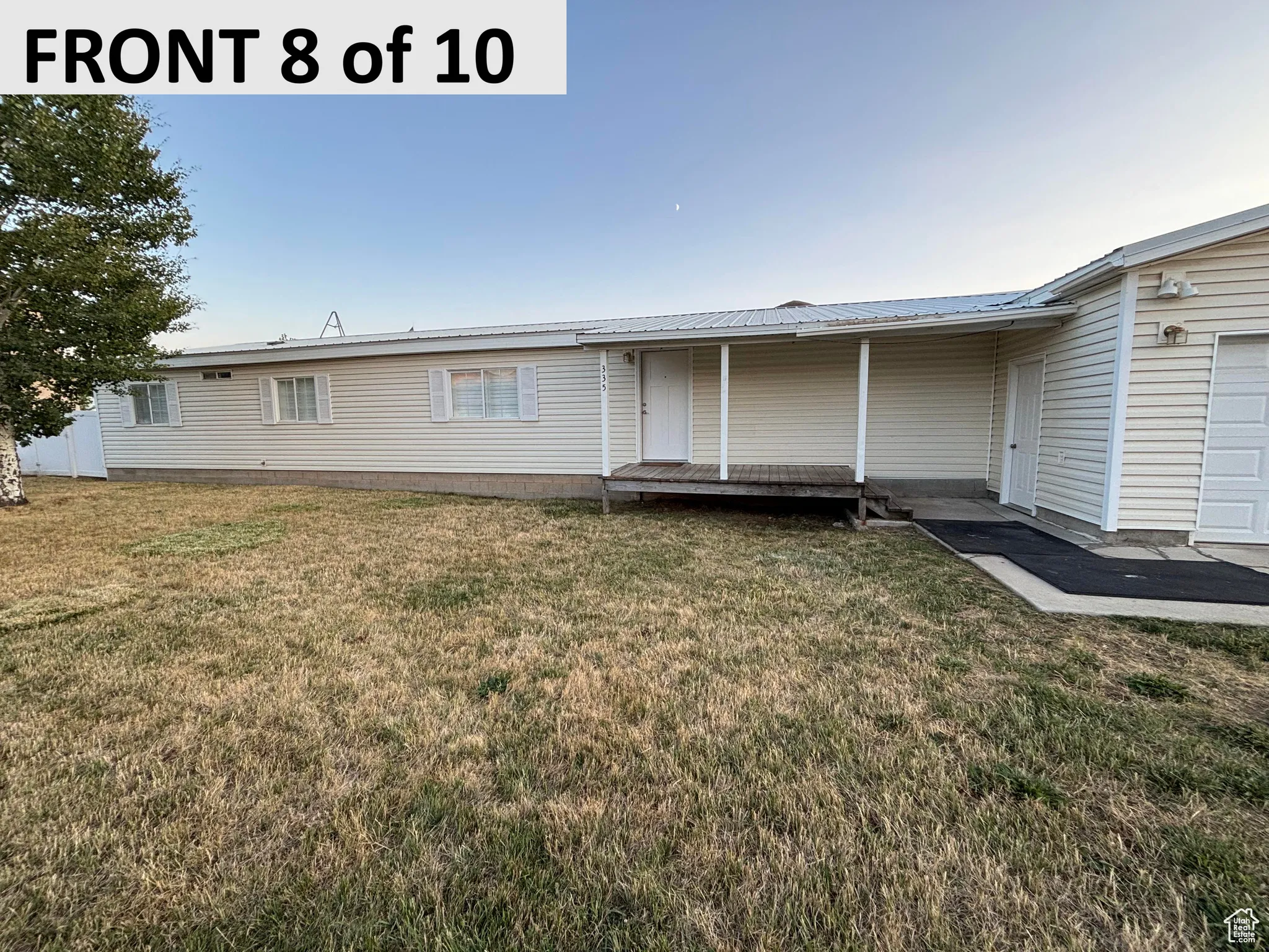 View of front of home with a front lawn, a metal roof, and a deck