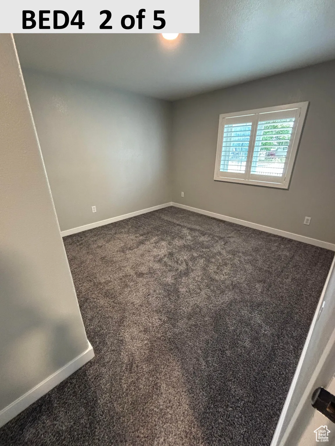 Bedroom 4 featuring dark colored carpet and baseboards