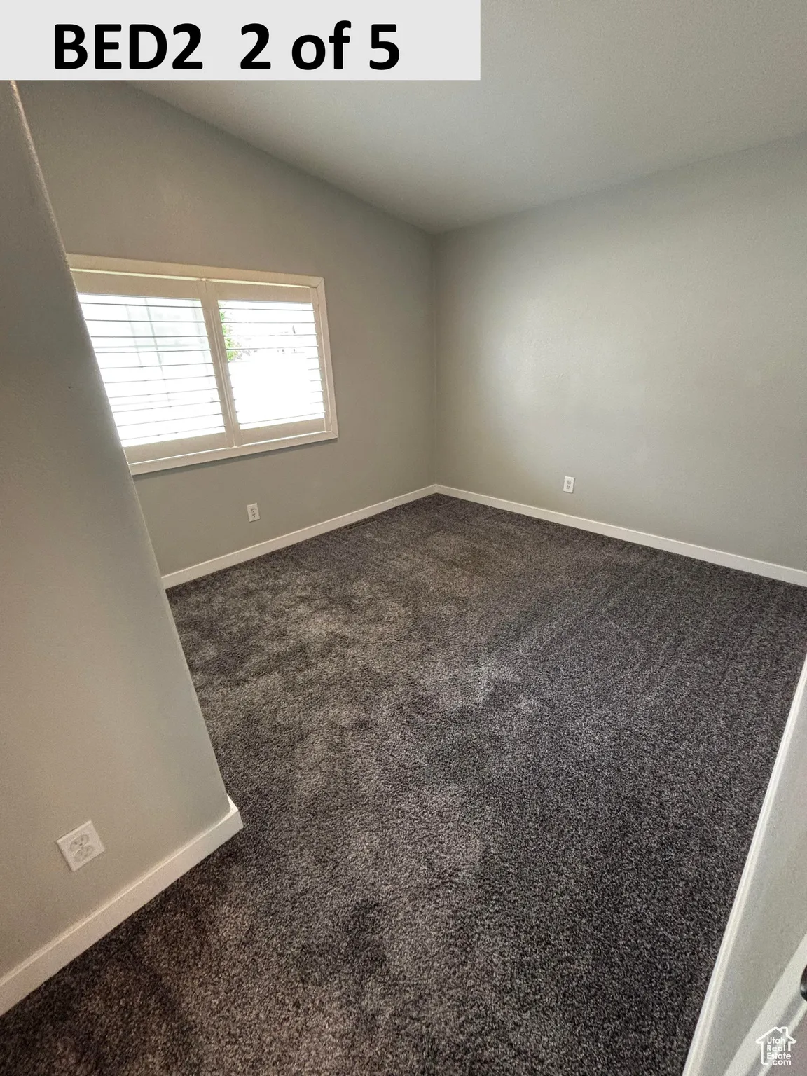Bedroom 2 with dark colored carpet and vaulted ceiling