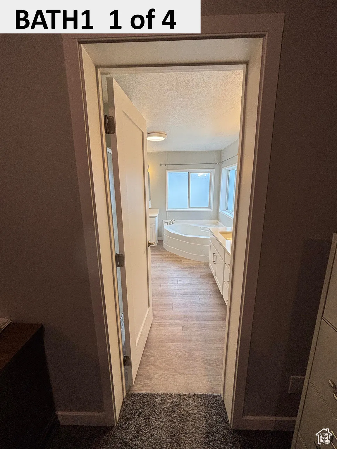 Master Bathroom with a garden tub, vanity, a textured ceiling, and light wood-style floors