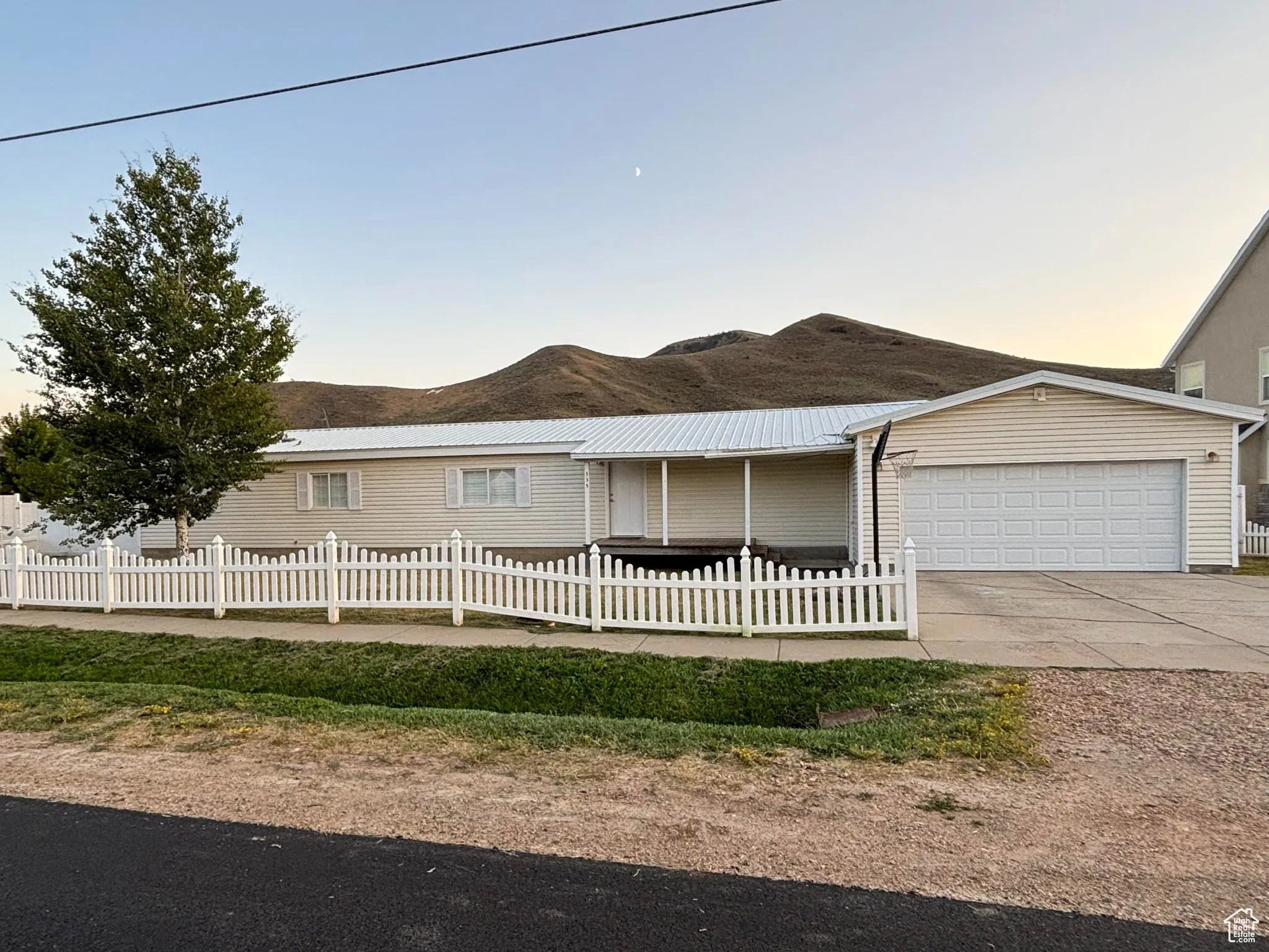 Ranch-style house with a fenced front yard, a garage, concrete driveway, and a mountain view