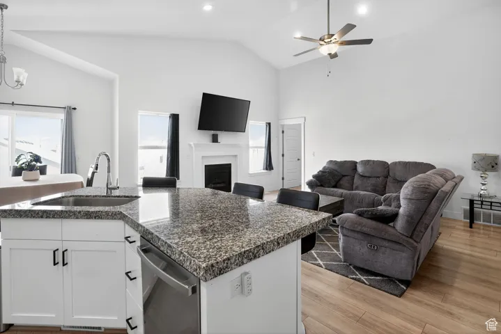 Kitchen with white cabinets, open floor plan, a fireplace, decorative light fixtures, and high vaulted ceiling